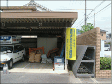 屋根の下に黄色い旗が置いてあってその左に回収箱が置かれている写真