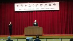 差別をなくす市民集会で舞台上で挨拶をする市長の写真