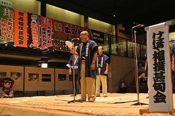 相撲館の土俵上にて相撲甚句を披露する相撲甚句会会員の写真