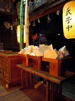 夜の神社で礼をする男性の写真