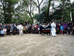 境内に広く設けられた仮田において、牛の仮面を付けた人と白装束の人が田をすく様子を演じている写真