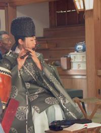 拝殿にて笛吹を奏上する神官の写真