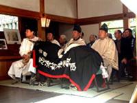 拝殿における神事に臨んで、参列者の最前列に腰かける「牛」と神官の写真