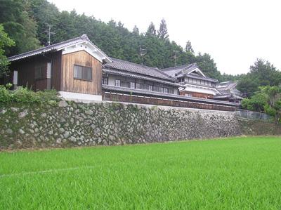 山林と水田の間にたたずむ古民家の写真
