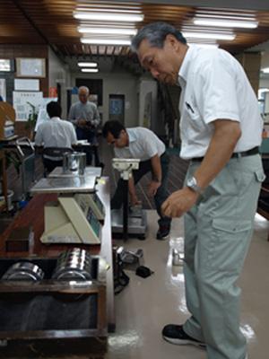 おもりを用いて計量器の検査をする男性の写真