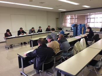 屋内でコの字型にテーブルが置かれ複数の男女が向かい合って座っている写真