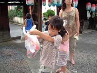 お供えのお下がりの中身を気にしている子どもの写真