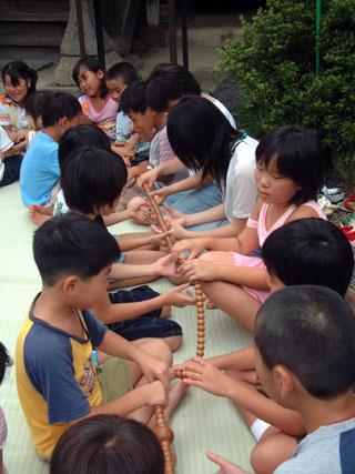 大きな数珠を回しながらお経を唱えている子どもたちの写真