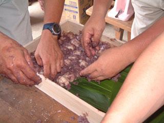 底にバランを敷いた木組みの枡のなかにあんをまぶした塩餅を並べている様子の写真