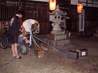 提灯のあかりのなかでバイクの後ろに石油缶をひもでくくりつけている写真