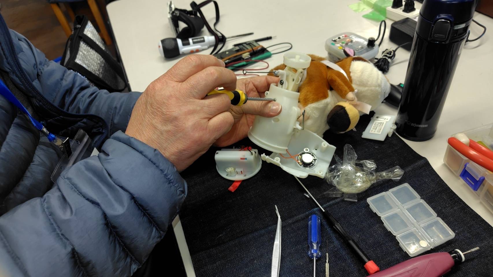 動くぬいぐるみをドライバーを使って修理している写真