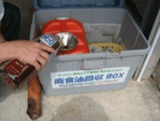 廃食油回収箱の赤いタンクに別な容器から廃食油を移している写真