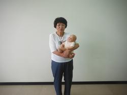 白い壁をバックに赤ちゃんを抱えた女性の写真