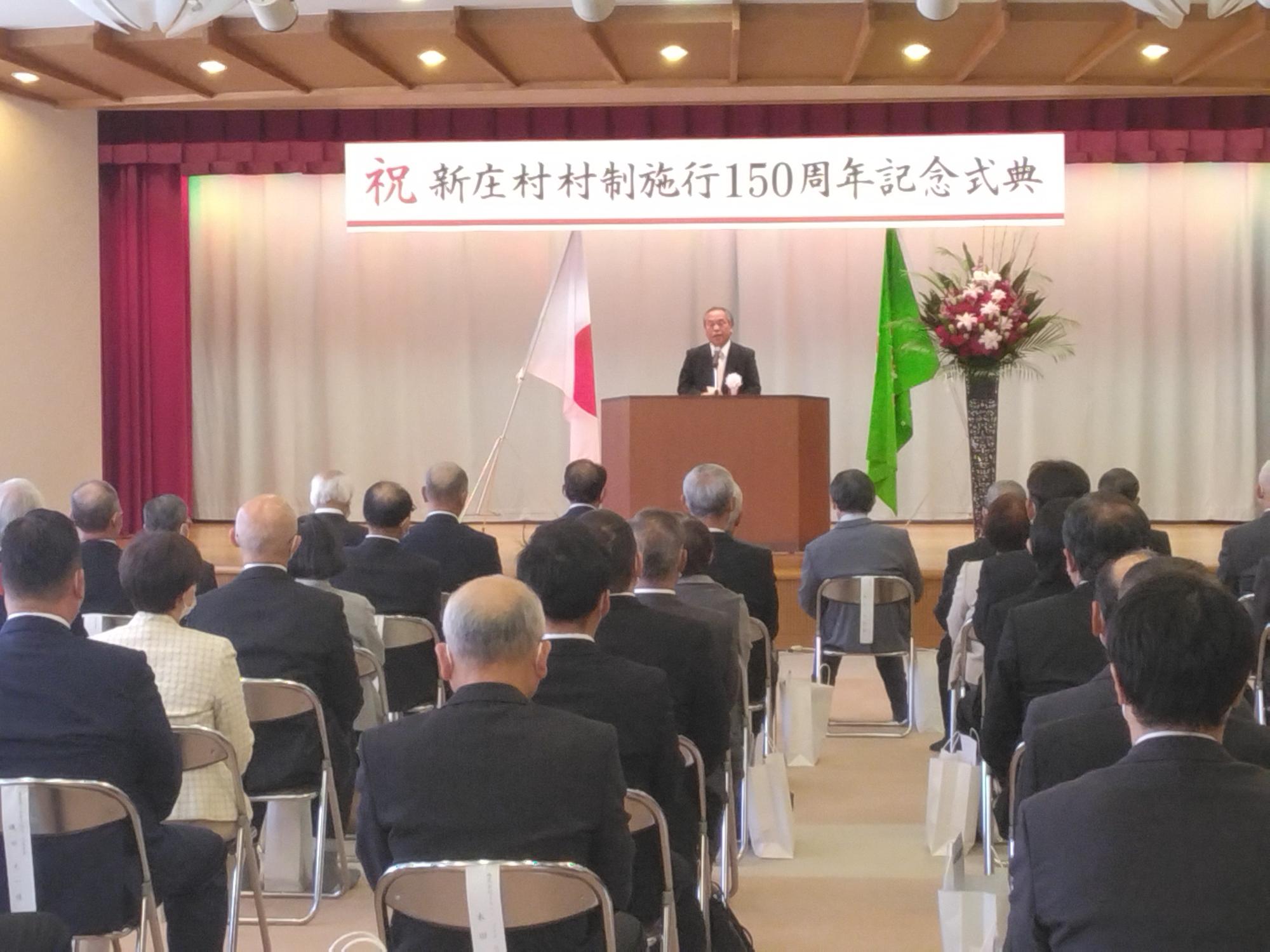 新庄村村制150周年記念式典で式辞を述べる小倉村長