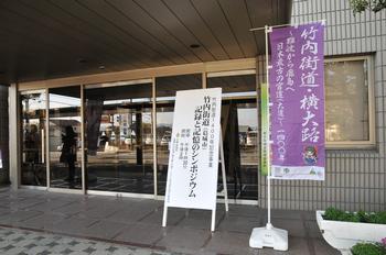 當麻文化会館の玄関前に竹内街道ののぼりとともに記録と追憶のシンポジウムに関する立て看板が設置されている様子の写真