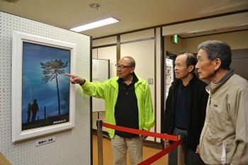 展示された「奇跡の一本松」の絵画と、それを鑑賞する来館者たちの写真
