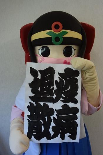 相撲字で疫病退散と書かれた紙を持つマスク姿の蓮花ちゃんの写真