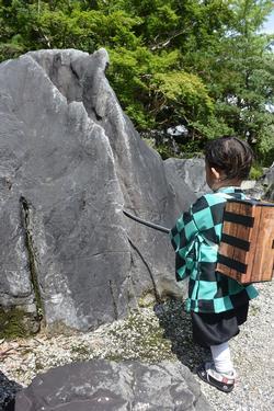 當麻寺奥院の巨石を前に、炭治郎に扮したファンが劇中の名シーンを再現している様子の写真