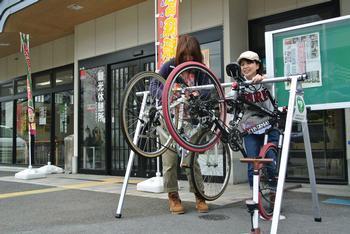 相撲館の前に設置されたスポーツサイクル用のラックを女性が利用している写真