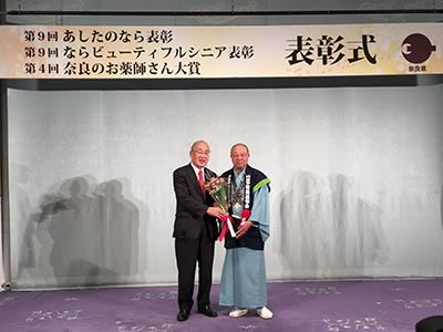 表彰に際し奈良県知事と記念撮影に応じる相撲甚句会会長の写真