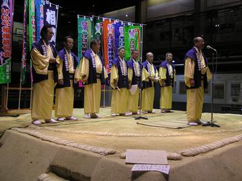 情報番組にエキストラ出演した甚句会の皆さんが相撲館の土俵の上で甚句を歌っている写真