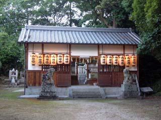 正面の軒先に灯がともった提灯が並べ吊り下げられている海積神社拝殿の写真