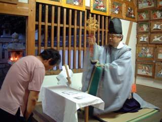 拝殿内で神楽鈴を手にした吉川宮司から祈祷を受ける参拝者の写真