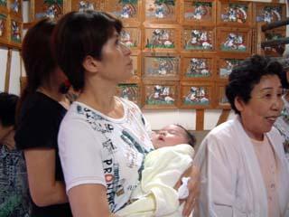 拝殿内で赤ちゃんを抱いて祈祷を待つ参拝者の写真
