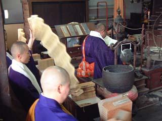 仏具の並ぶ中、僧侶により転読が行われている様子の写真