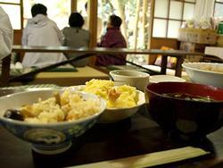 屋内にて炊き込みご飯や汁物、おかず等が並んでいる様子の写真