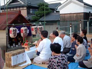 春日神社の祠の前で正座して心経を斉唱している人たちの写真