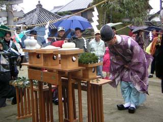 拝殿前の屋外にて、御饌を前に神事を執り行う神官の写真