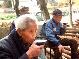 椅子に座って受けとった甘酒を飲む参拝者たちの写真