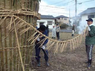 できあがった注連縄をトンドに巻き付けていく作業の写真