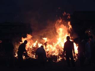 まだ火が燃え残っている焼け落ちたトンドに集まる参加者たちの写真