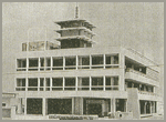 三階建ての建物の上に小さな三階建ての塔のようなものが立っている當麻町役場新庁舎の外観の白黒写真