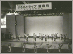 ステージ上で人々が何かの出し物をしている白黒の写真