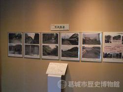 スポットライトが当たっている額縁に上下2枚ずつ写真が並べられた、竹内街道を紹介する展示風景の写真