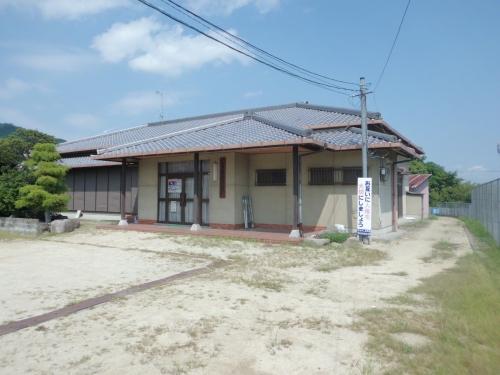 瓦葺の屋根でクリーム色の壁になっていて、真ん中に扉の入口がある太田集落センターの外観写真