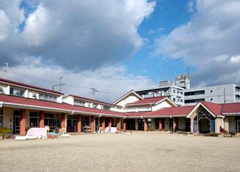 広々とした園庭から見た赤い屋根の忍海小学校付属幼稚園の写真